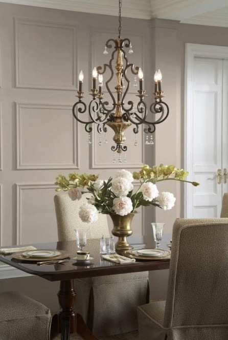 chandelier over a dining table that has flowers and plates