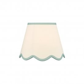 A neutral scalloped edge table lamp shade with blue accent edging