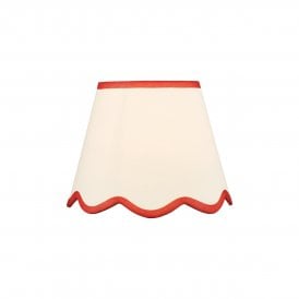 A neutral scalloped edge table lamp shade with red accent edging